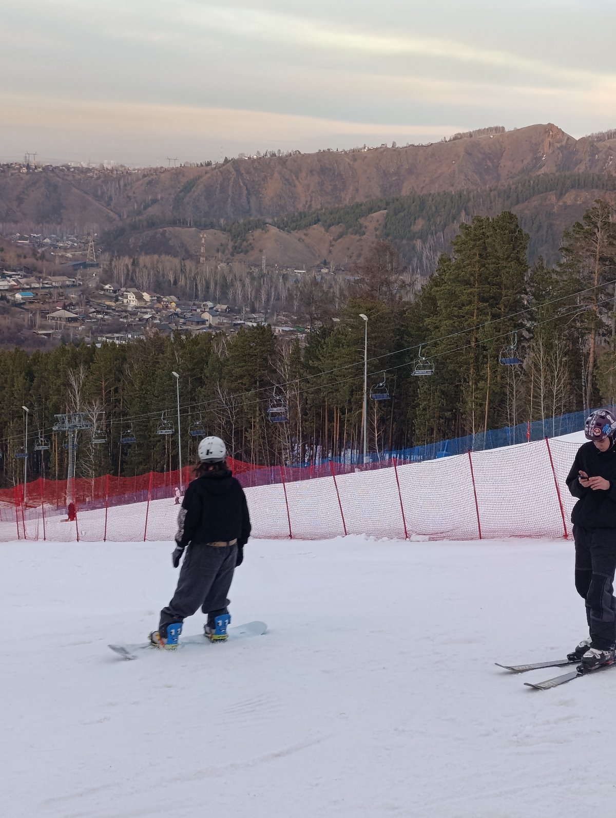 Skiers ride chairlifts at Krasnoyarsk resort with city views