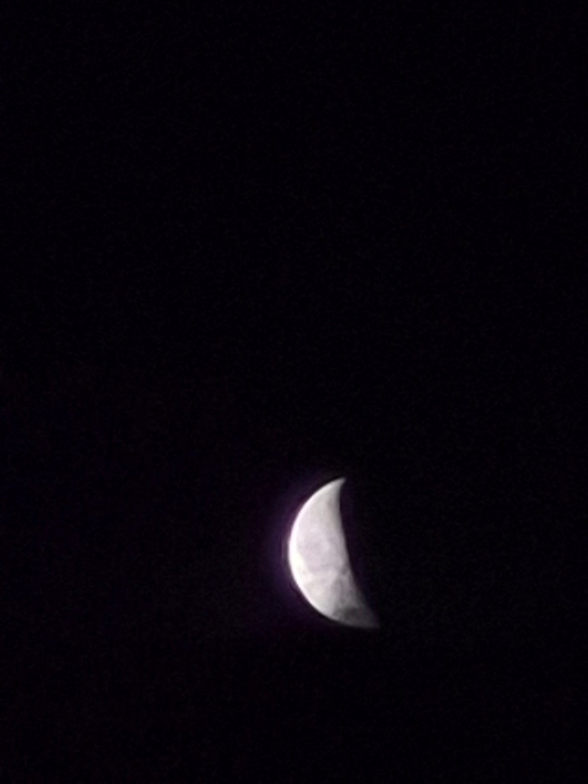 Crescent moon drifts through cloudy skies over rural Estonia