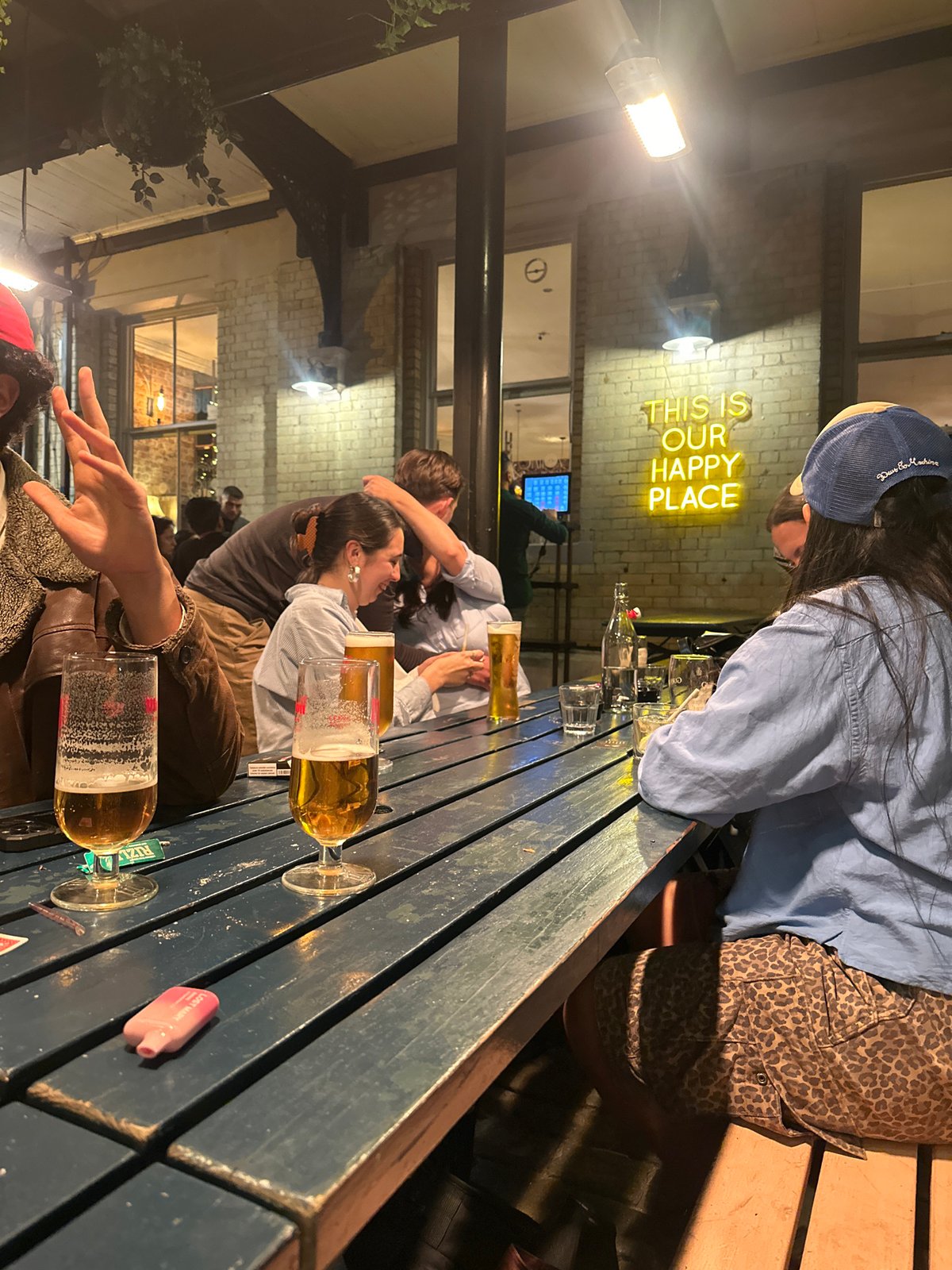 Evening gathering at London outdoor bar with neon signage