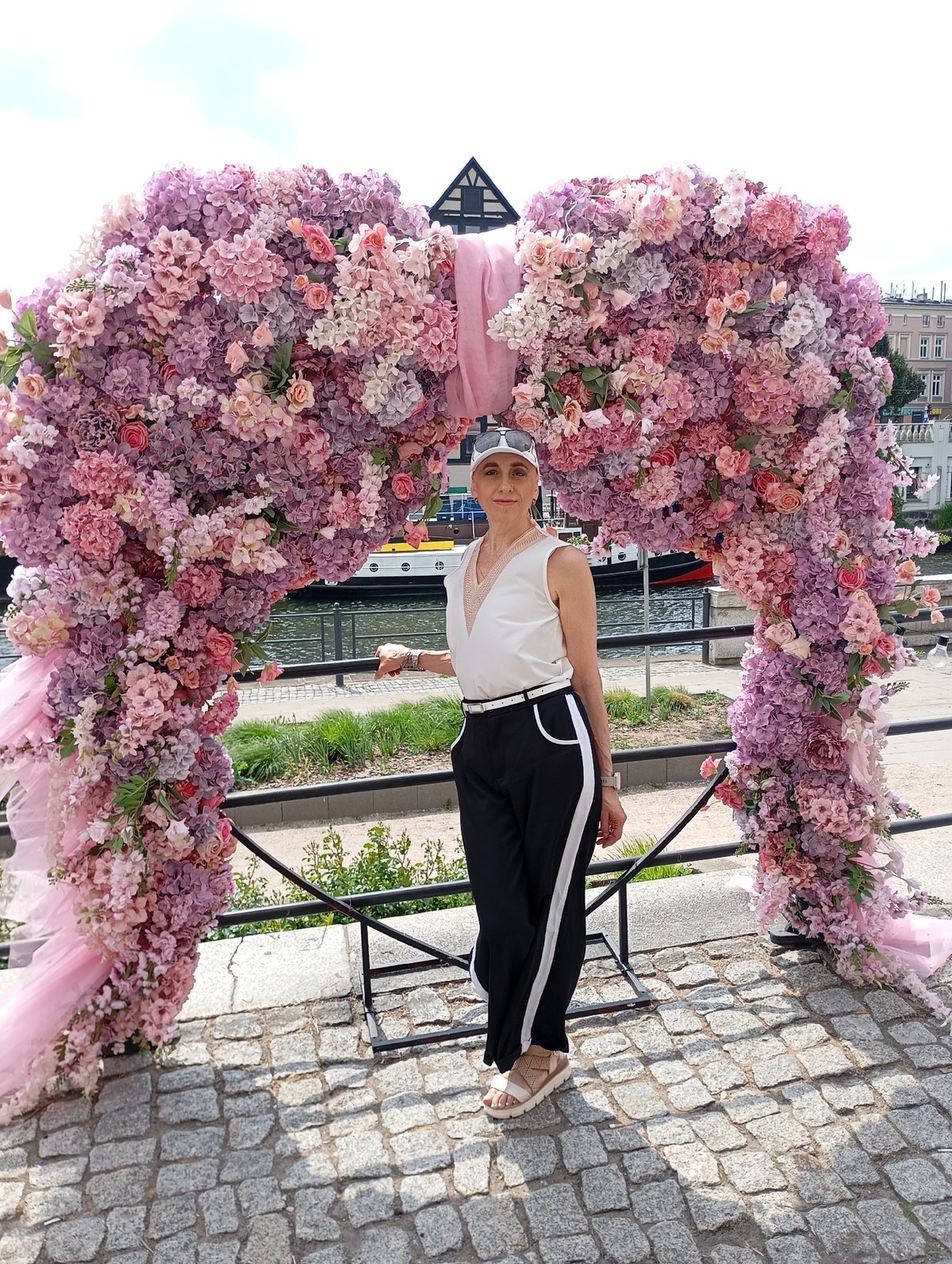 Woman poses beneath floral archway in Bydgoszcz, Poland
