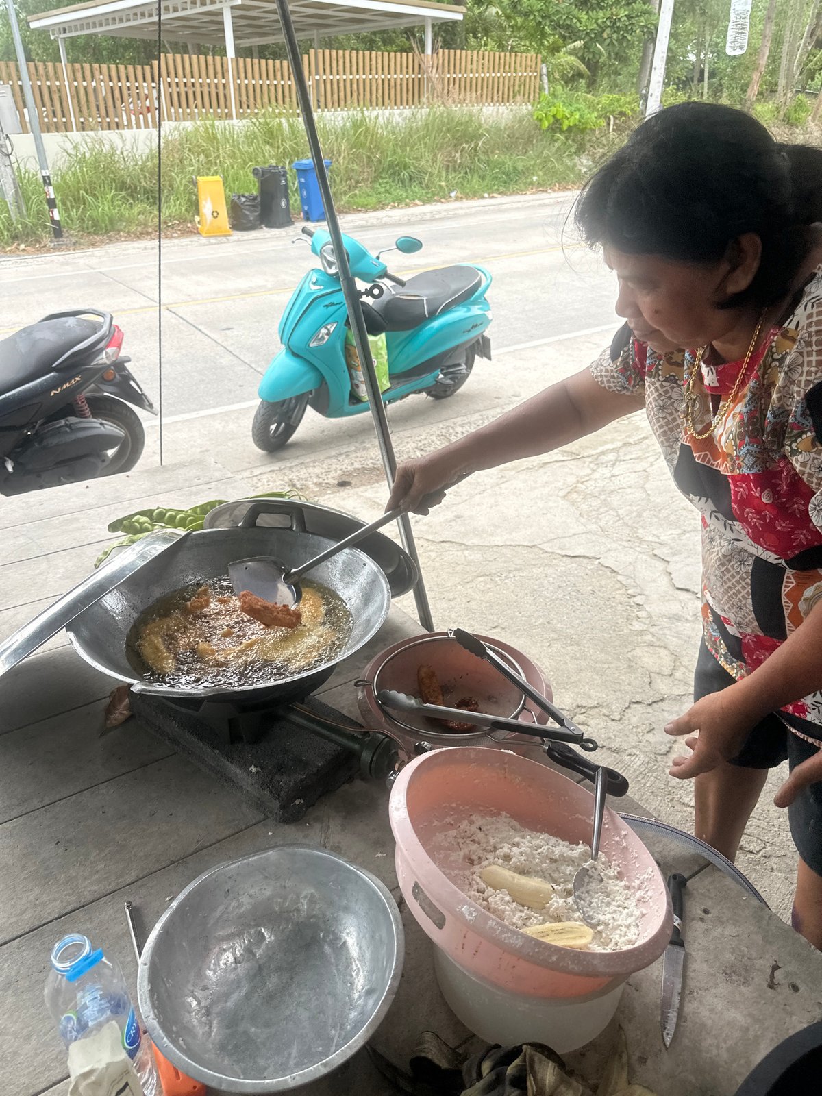 Woman fries banana fritters outdoors in Ko Phangan, Thailand