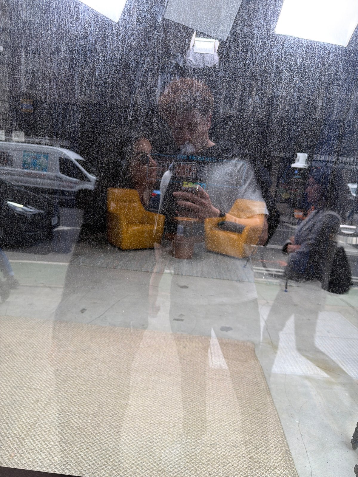 Person with yellow container photographed through dirty window in NYC