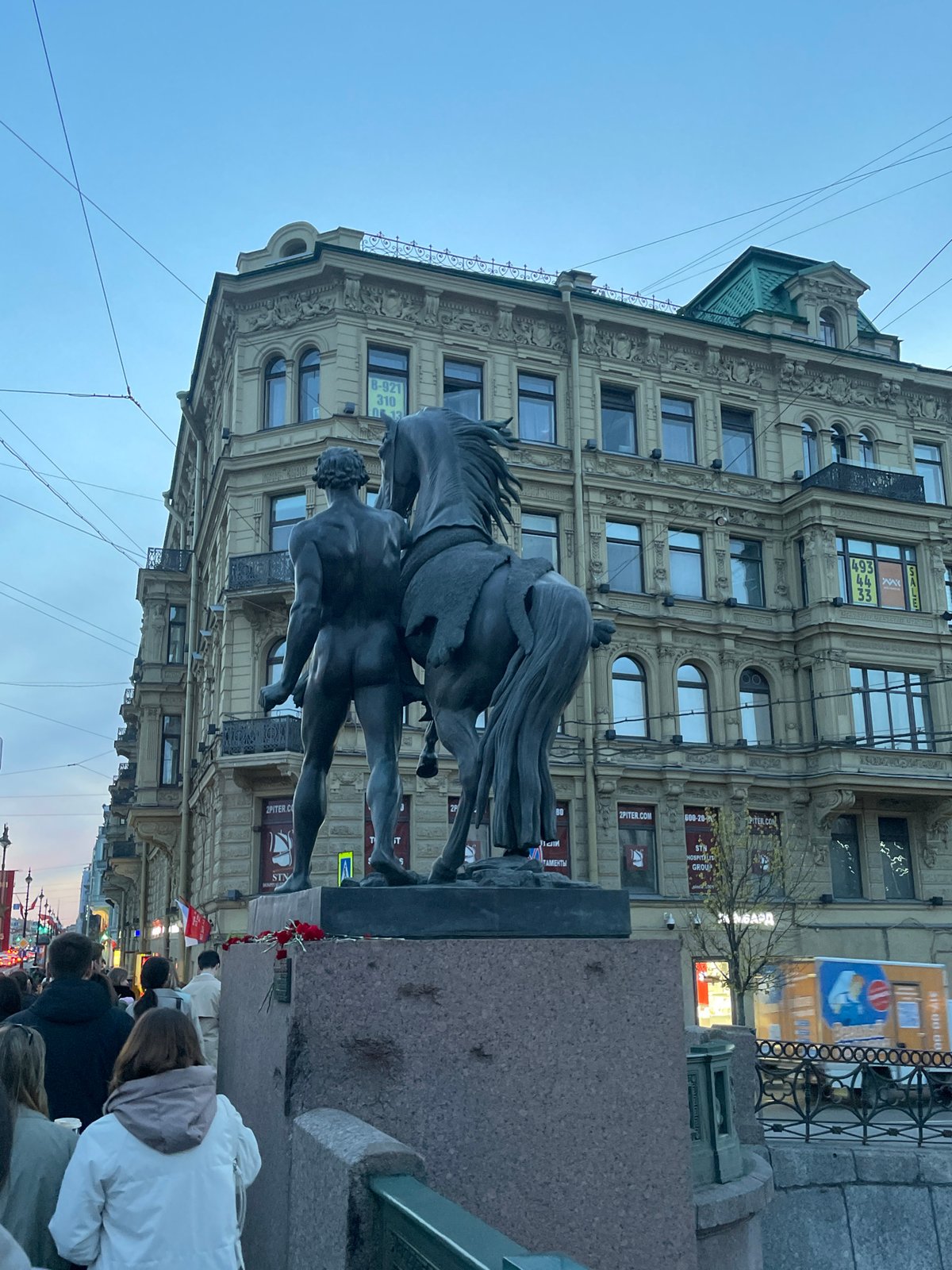 Evening pedestrian activity documented near historic statues in Saint Petersburg