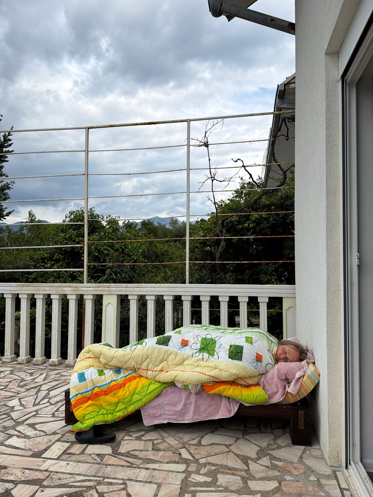 Woman naps on balcony bench in Montenegro village