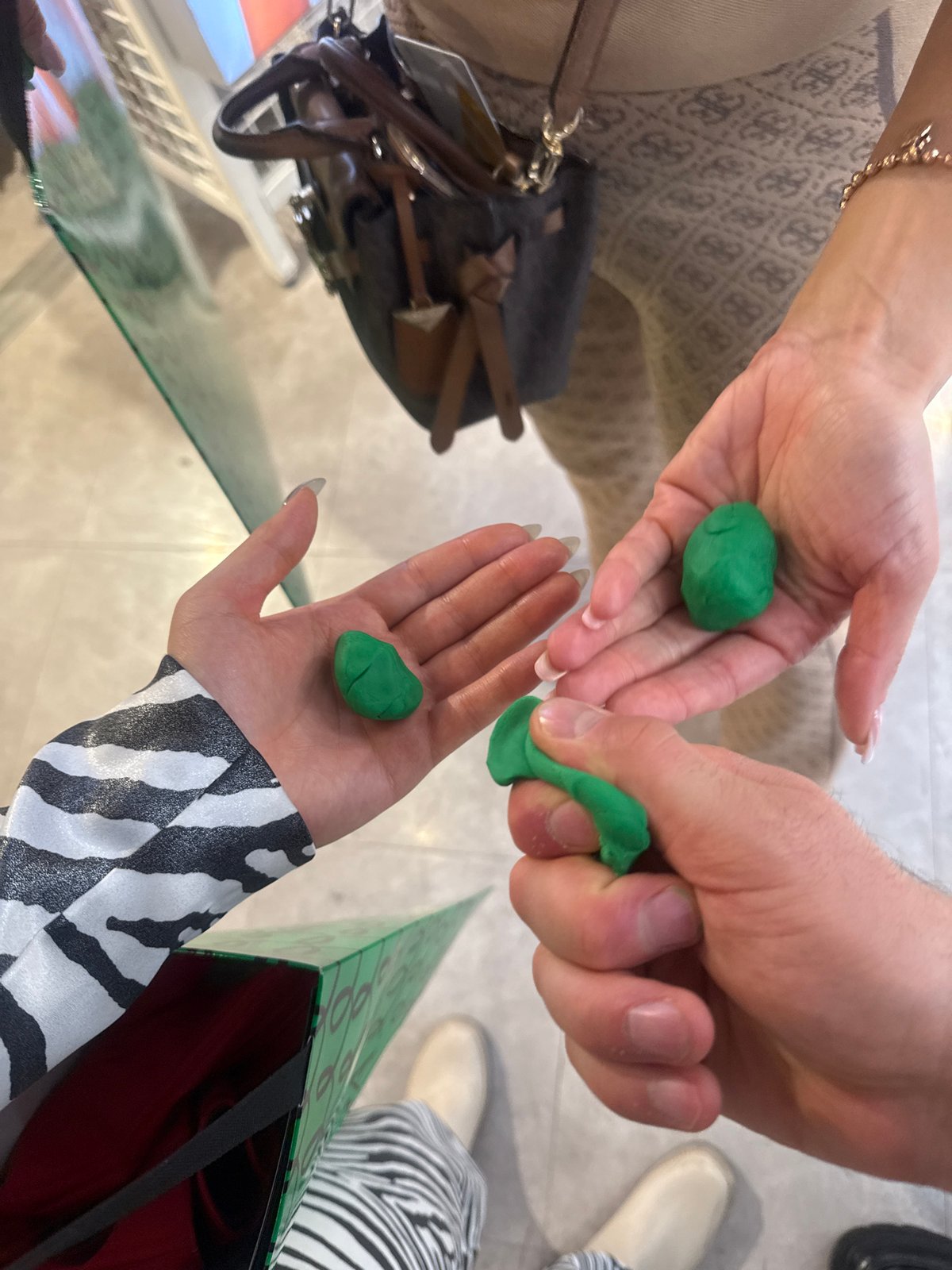 Three people play with green playdough in Milan