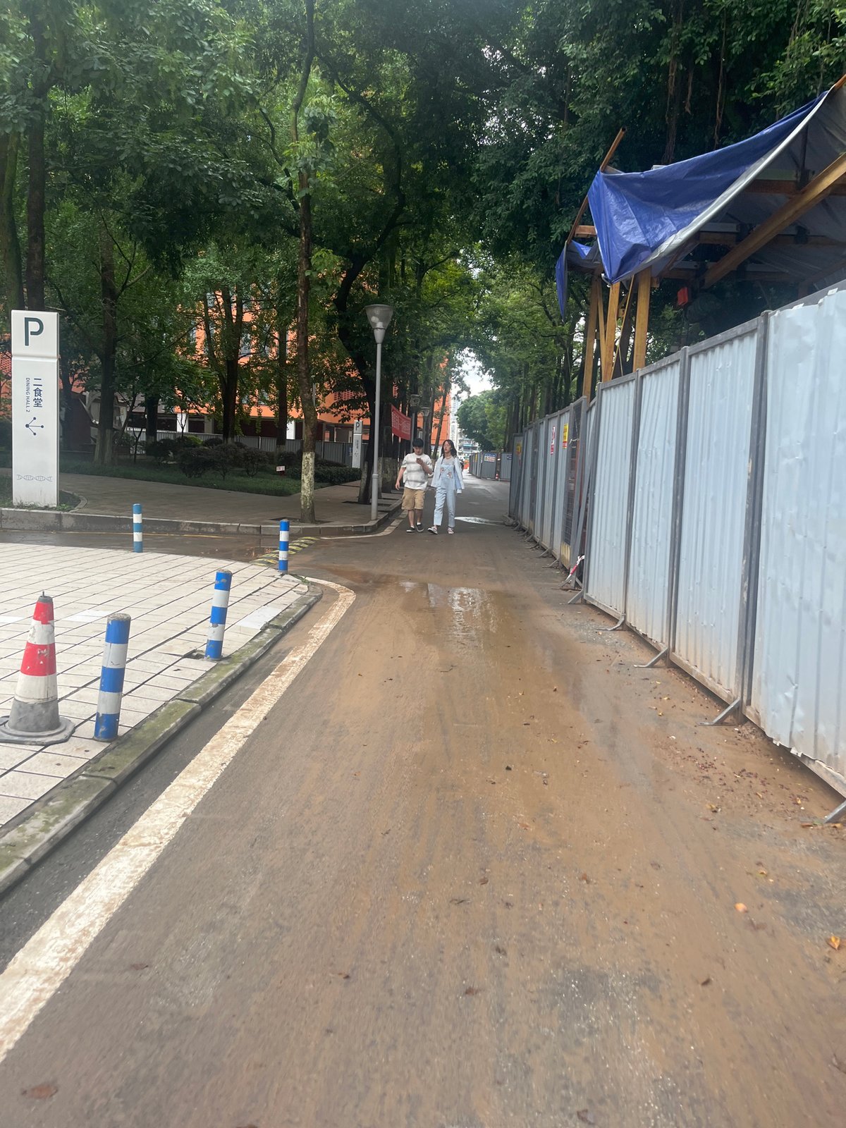 Two pedestrians walk muddy street in Yuzhong District