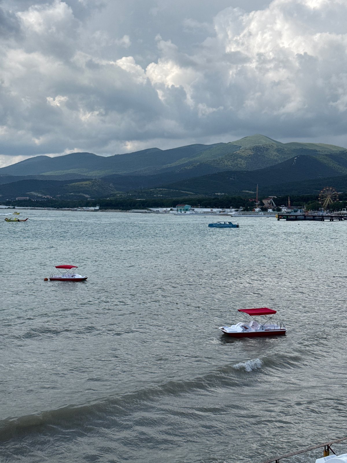 Cloudy beach day in Novorossiysk with pedal boats and crowds