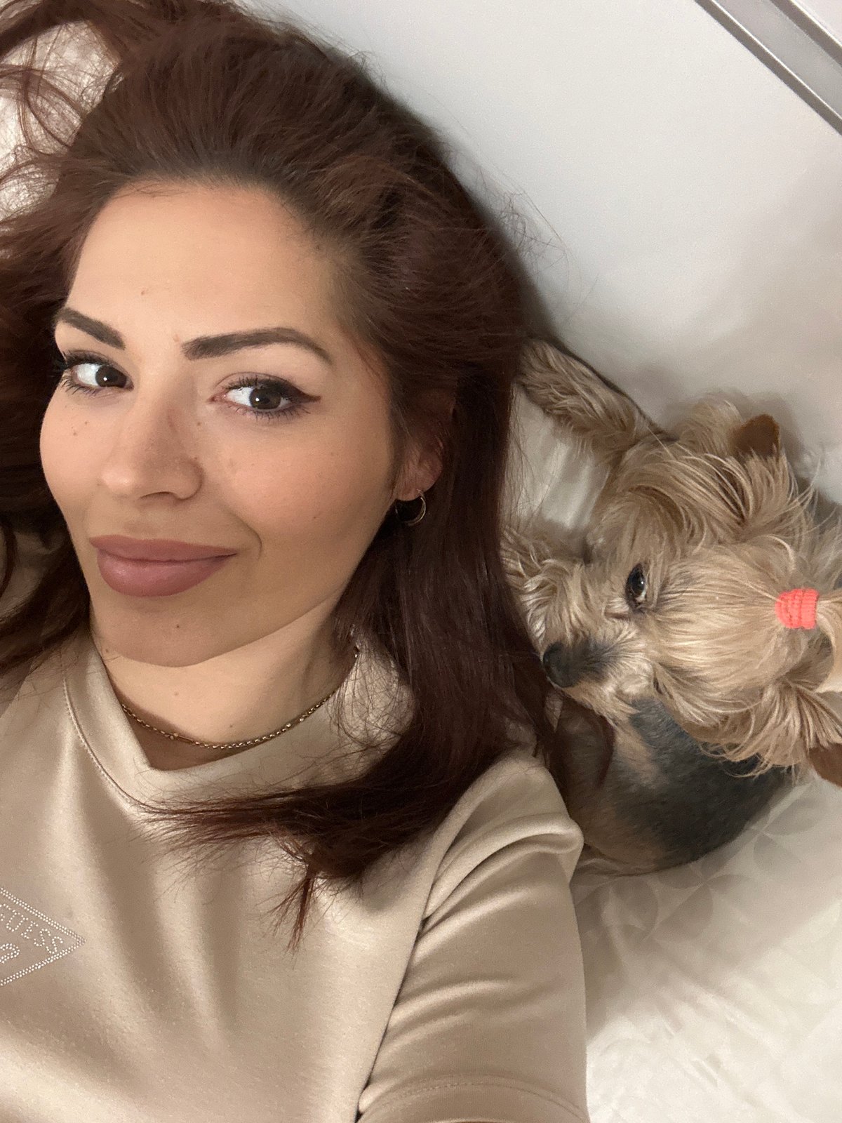 Woman and Yorkshire Terrier rest together on bed in Sofia