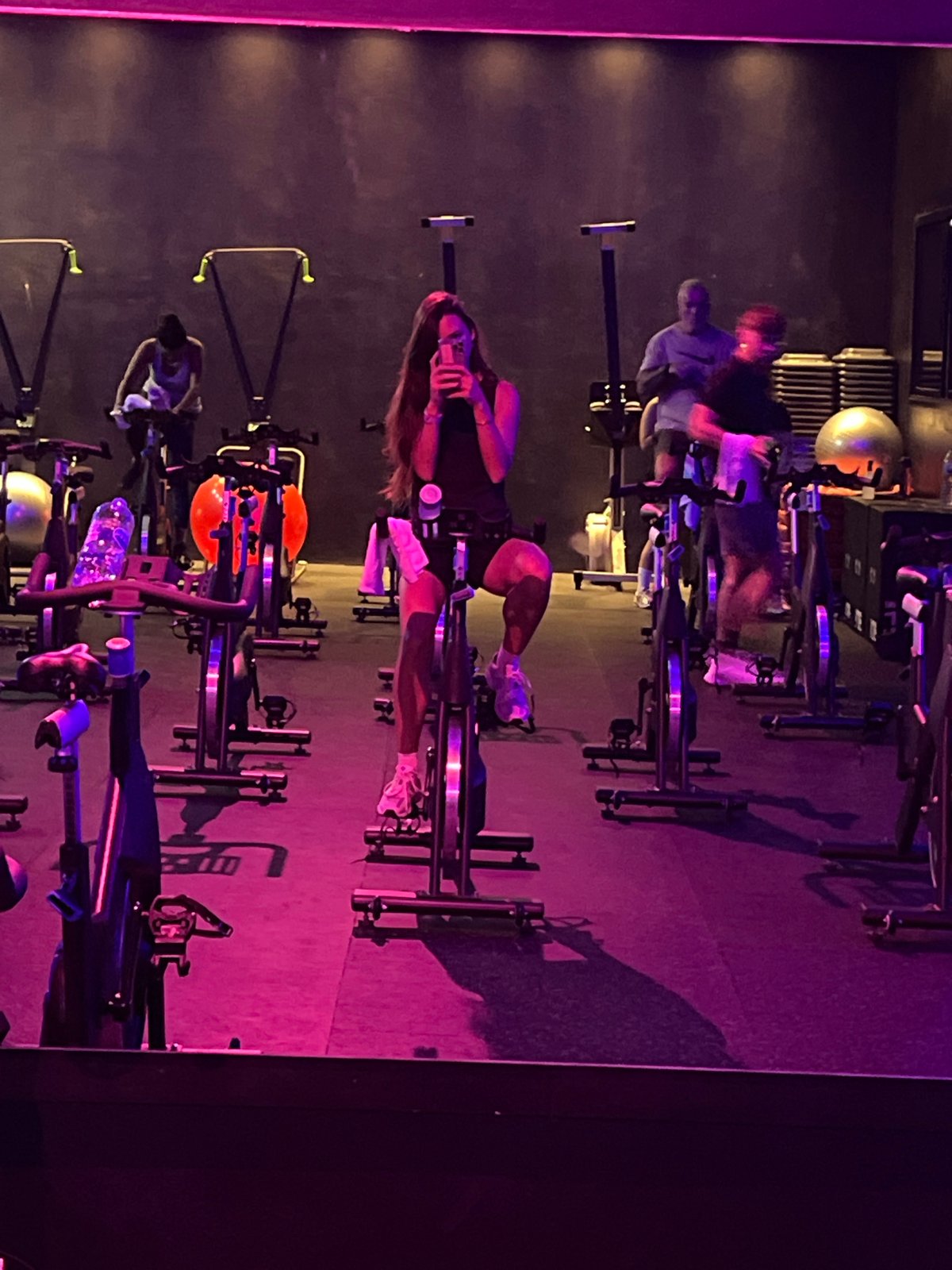 Early morning cycling class captured in purple-lit fitness studio