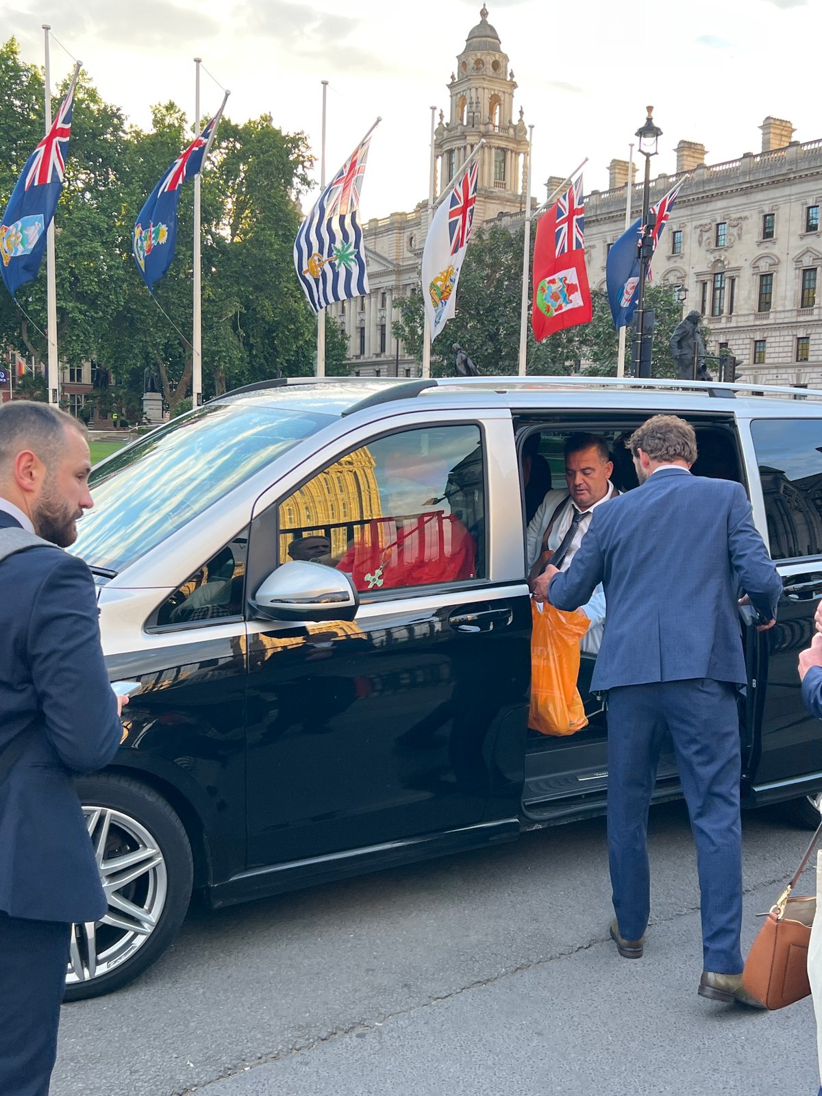 Suited man exits minivan with orange bag in London