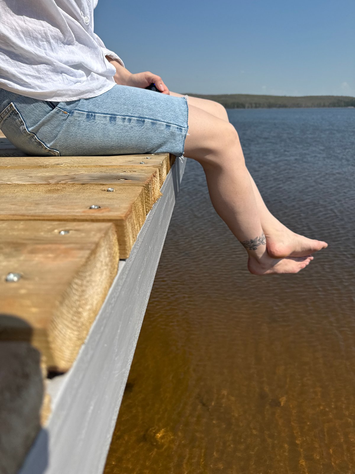 Woman enjoys quiet morning moment on wooden dock in Chaikovsky