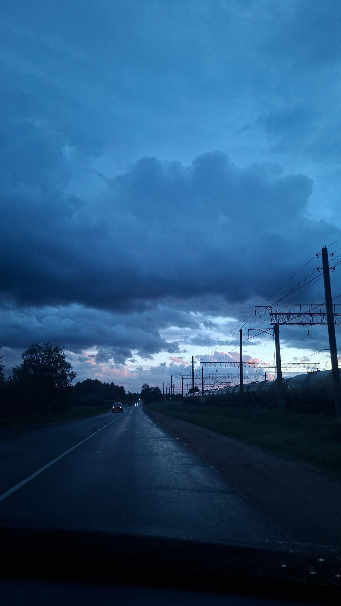 Vehicle travels wet road in Смалявічы, Belarus evening