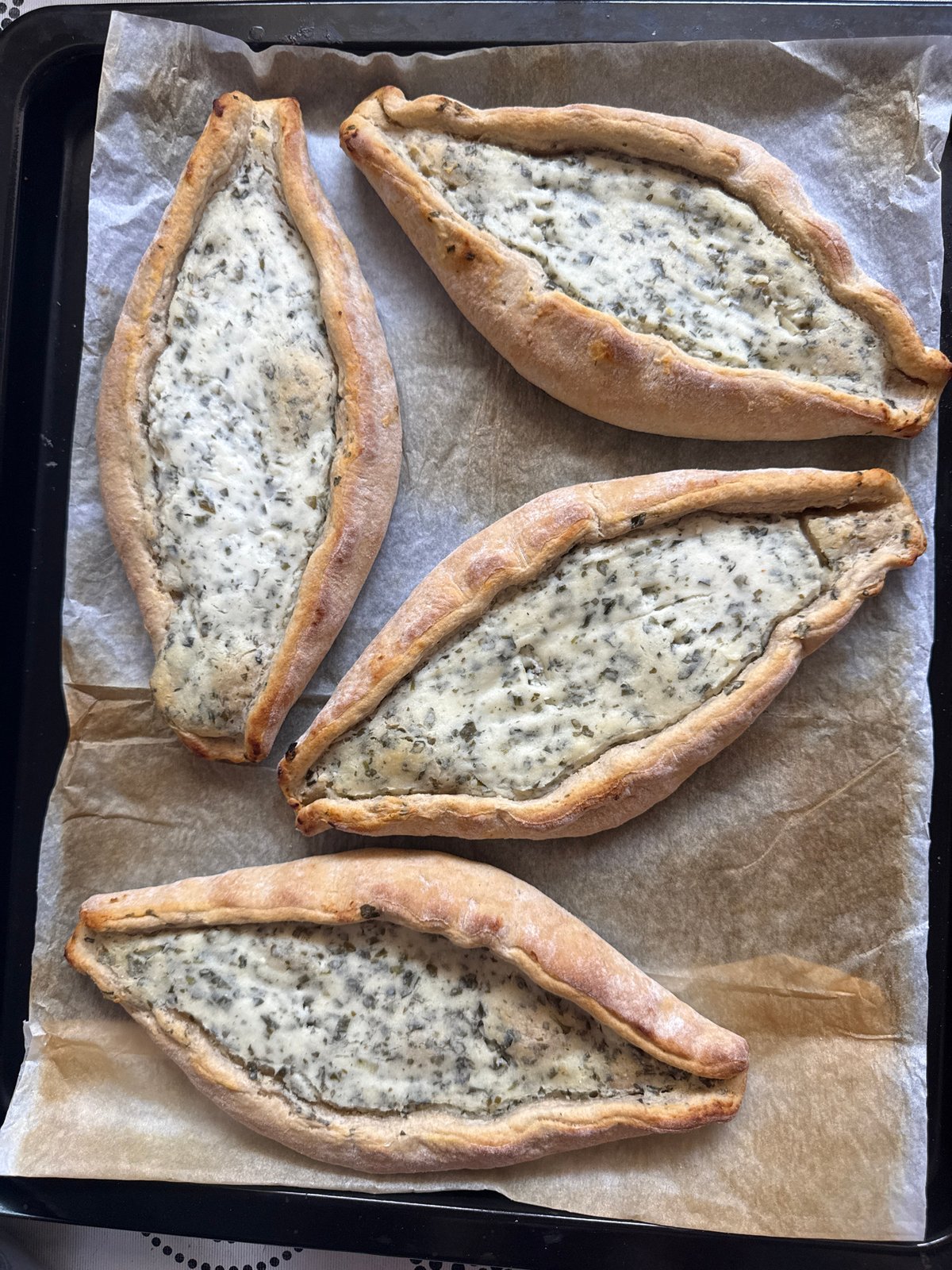 Four herb-filled boat pastries documented on baking sheet