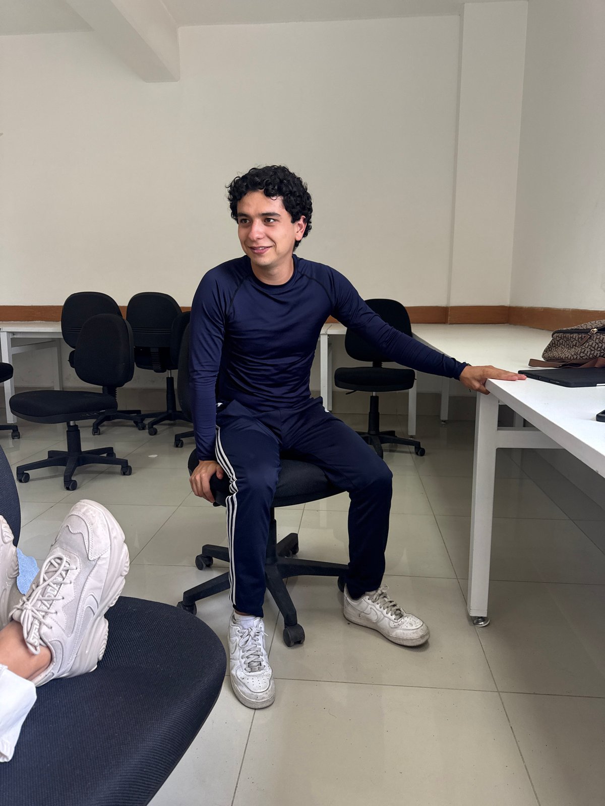 Man in tracksuit sits in office chair, San Andrés Cholula