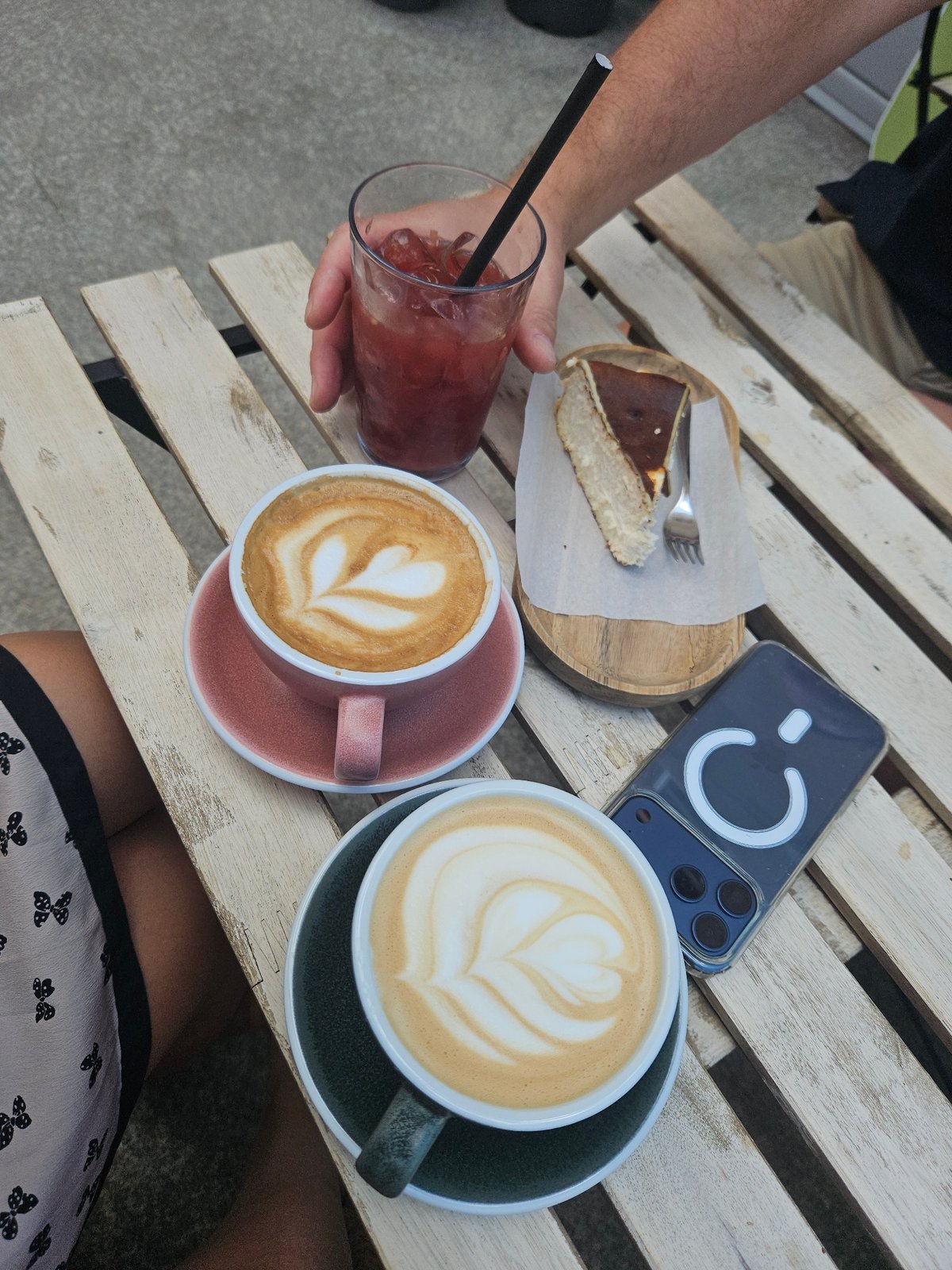 Café table with lattes, cheesecake, and iced drink, multiple angles