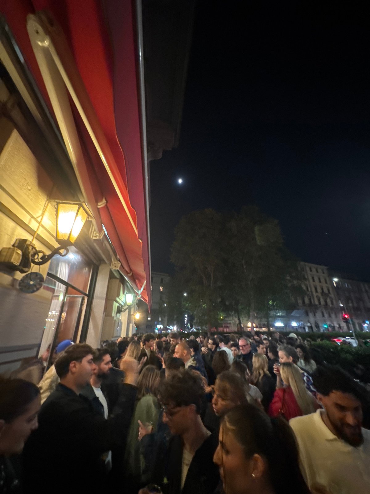 Evening crowd gathers on Milan street near local establishments