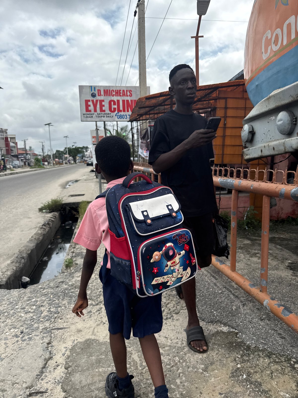 Afternoon street life in Ado, Nigeria — students and passersby
