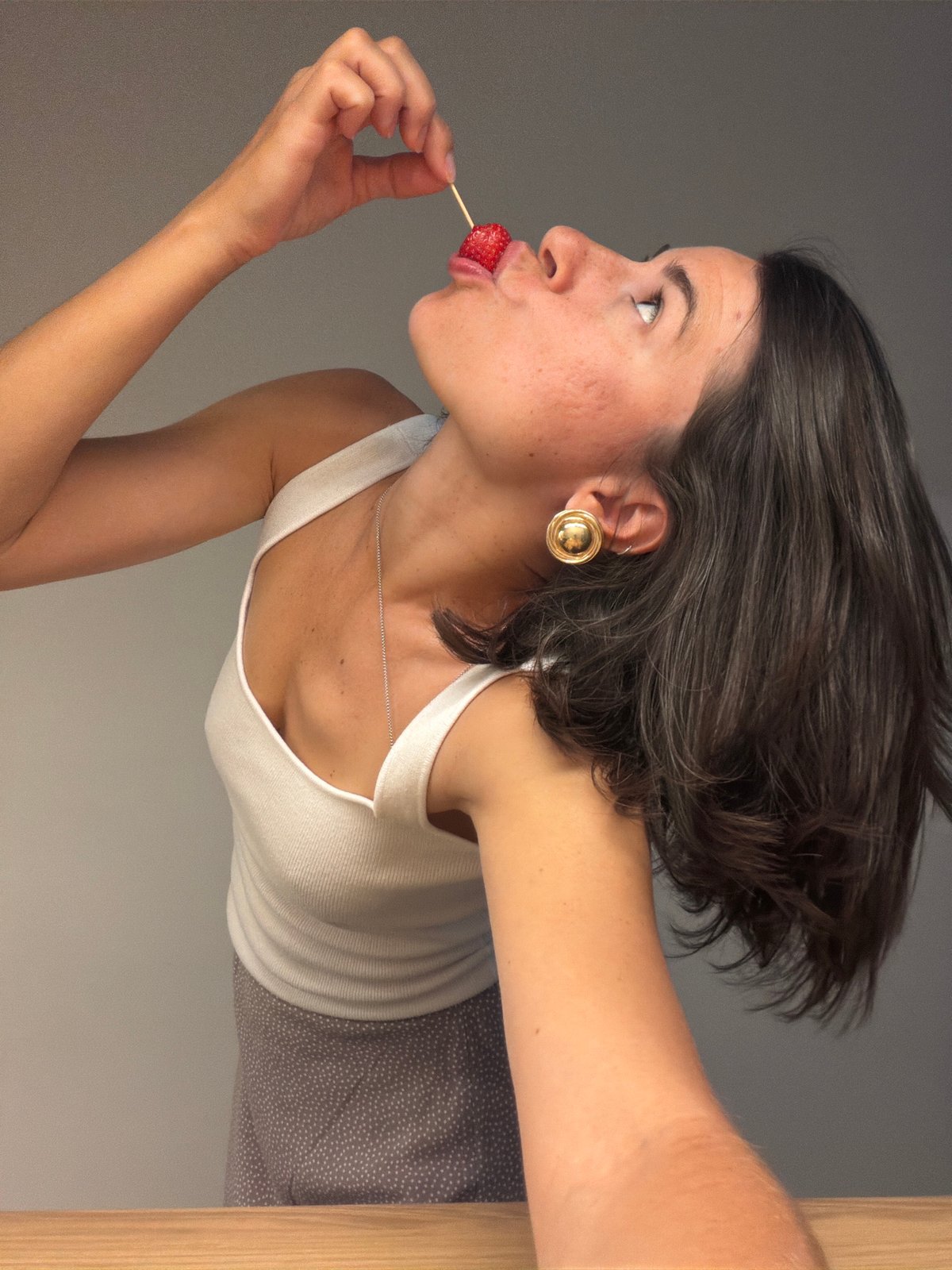 Woman poses playfully with strawberries and Buddha statue in Montenegro