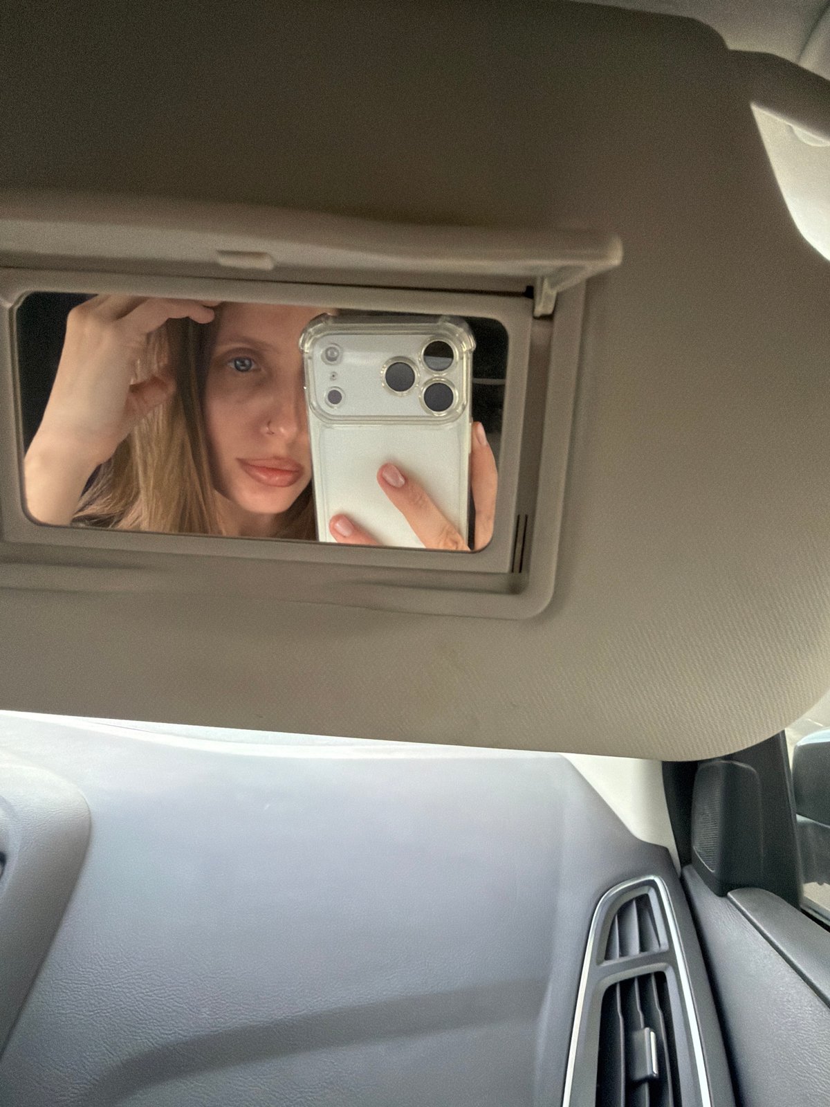 Person takes selfie in car sun visor mirror