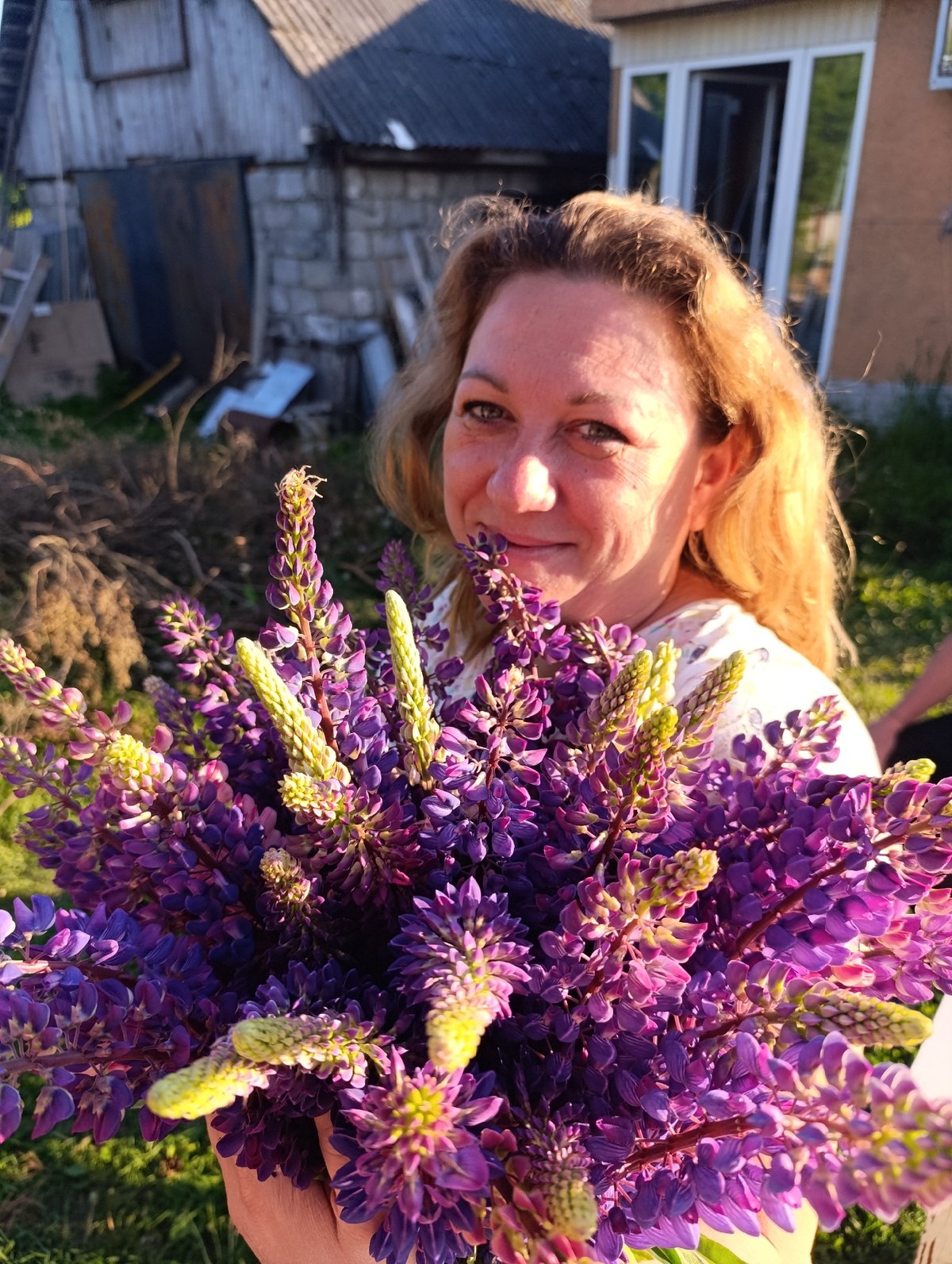 Woman photographed with lupine bouquet in rural outdoor setting