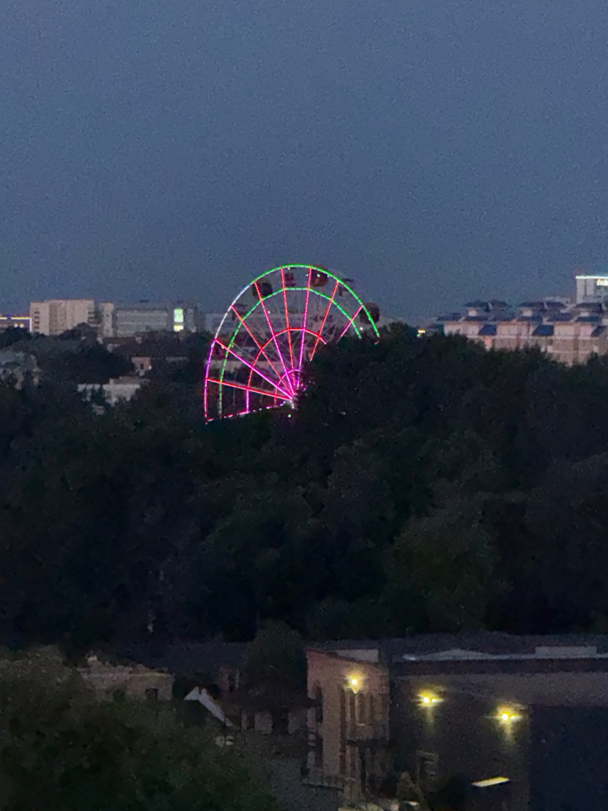 Brest at dusk: Ferris wheel lights and a red moon rising