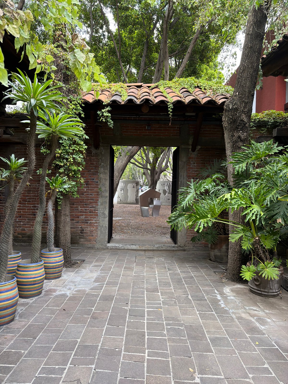 Vegetation-covered brick archway frames artistic alleyway in Puebla