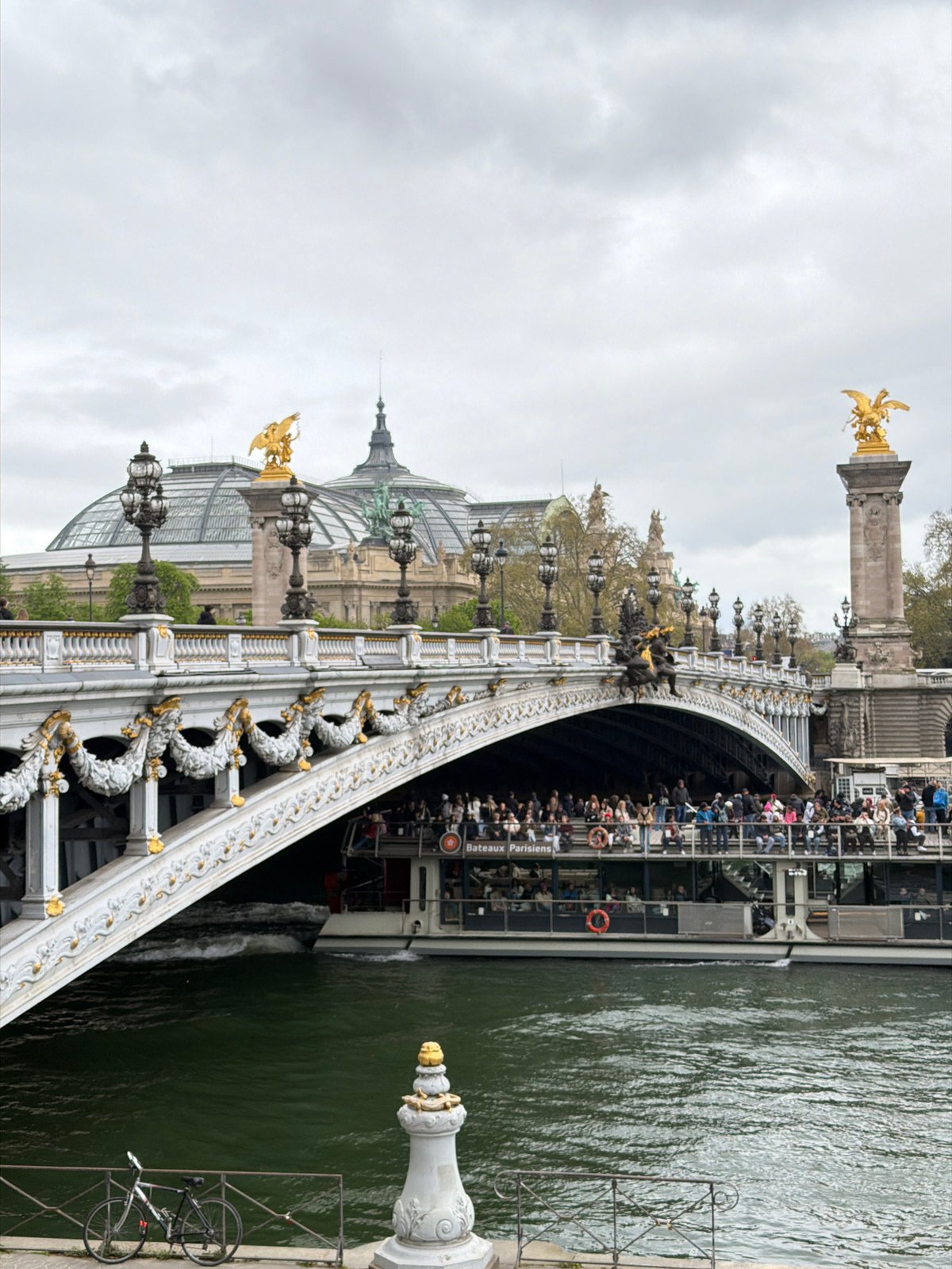 Tourist boat passes under ornate Pont Alexandre III in Paris