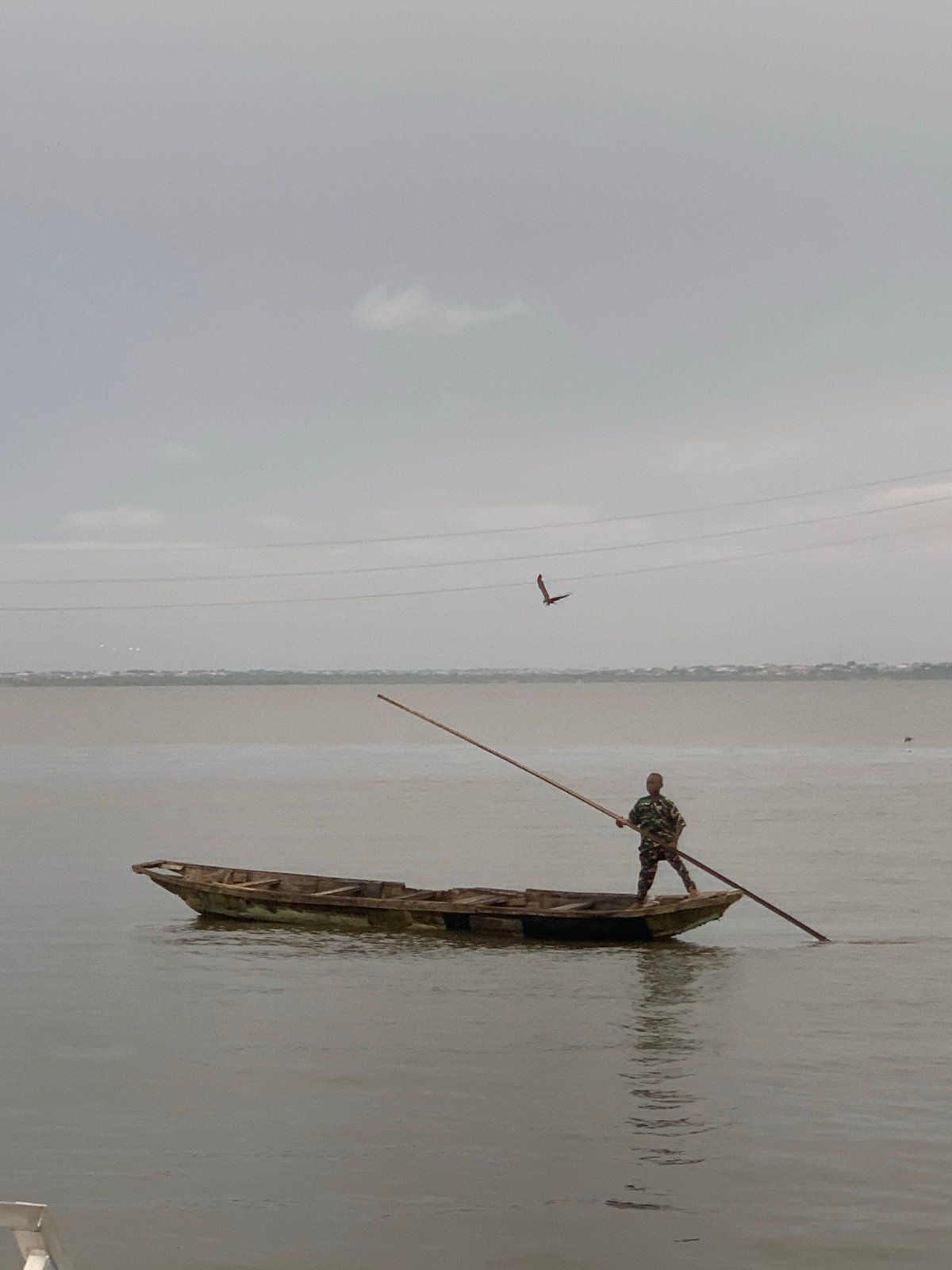 Man poles wooden boat in waters near Ikoyi, Nigeria