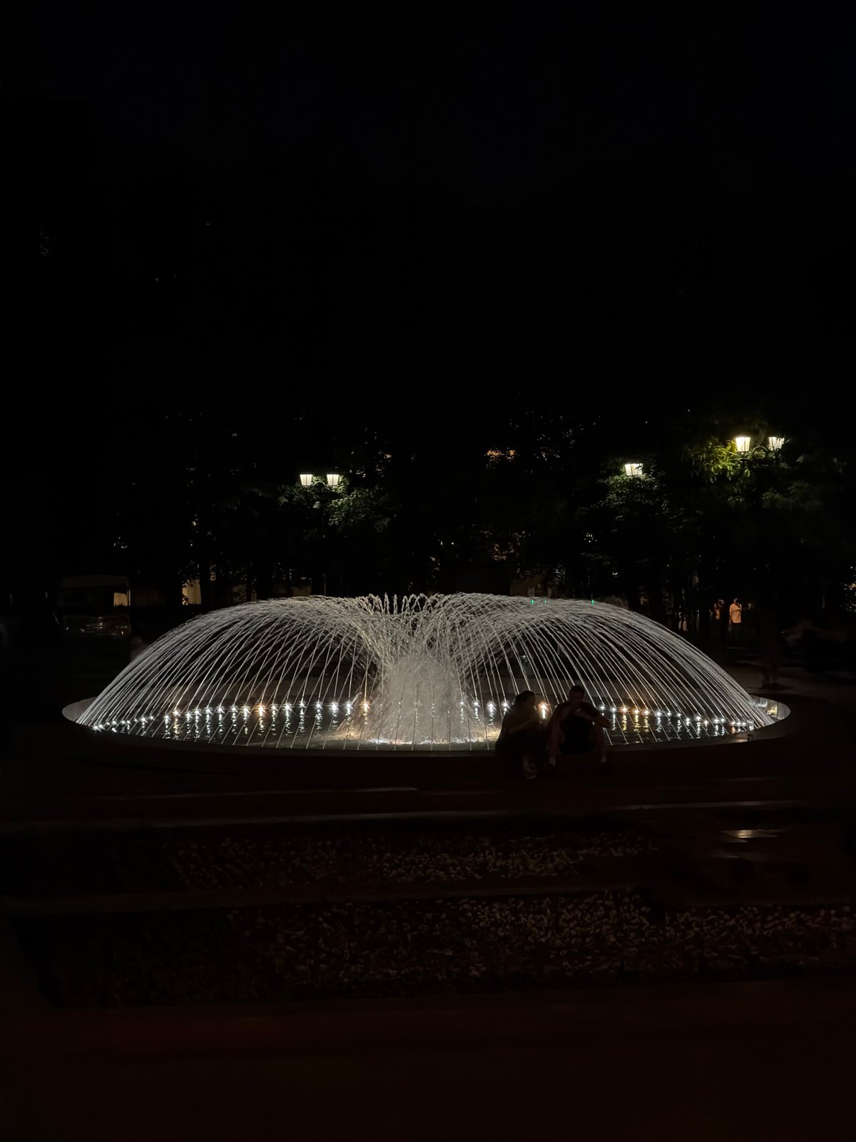 Evening fountain scene witnessed in Moscow with figures nearby