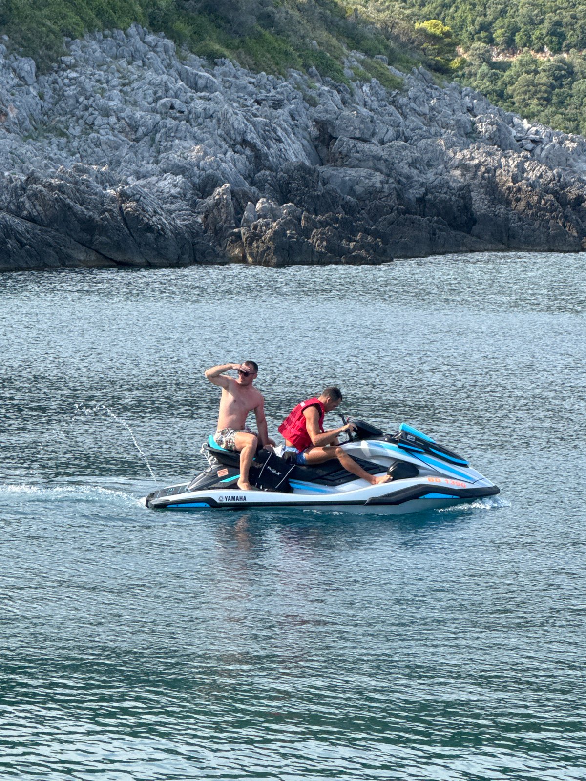 Jet skiing along Montenegro's rocky Adriatic coast on a sunny afternoon.
