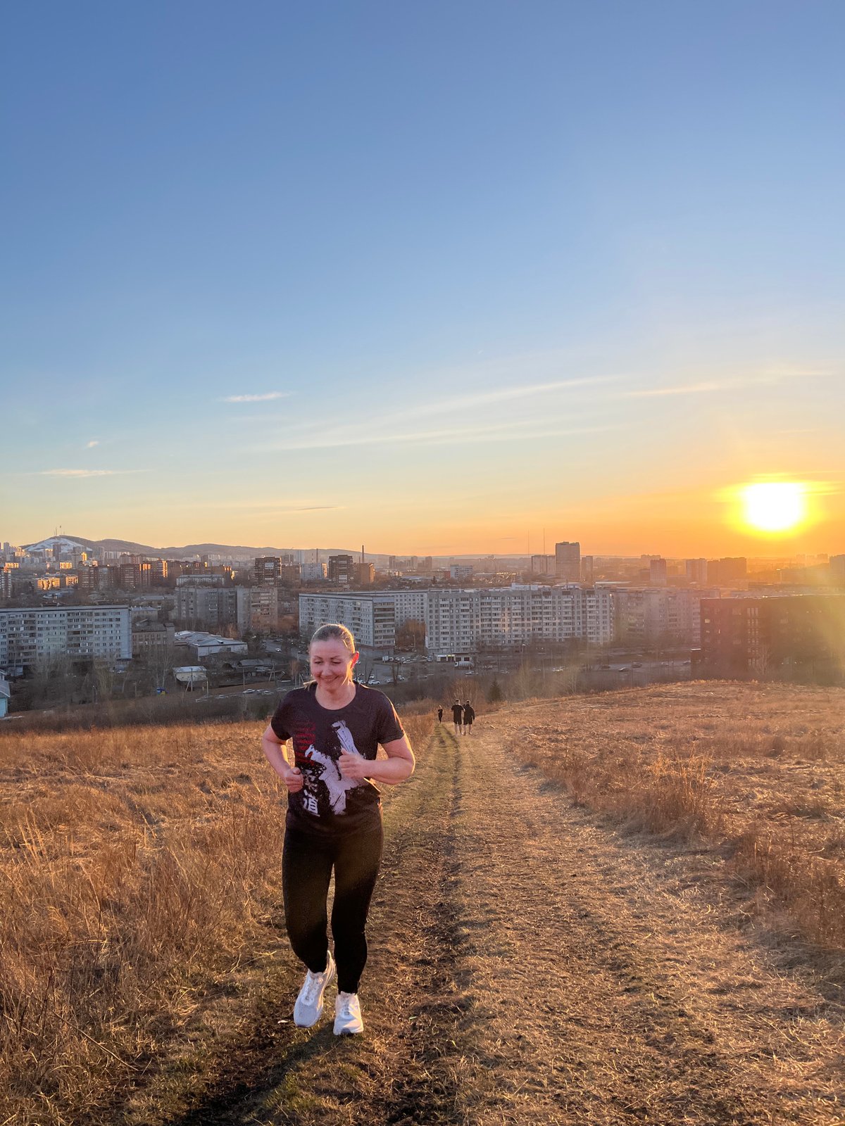 Woman photographs overlooking Krasnoyarsk during golden hour moment