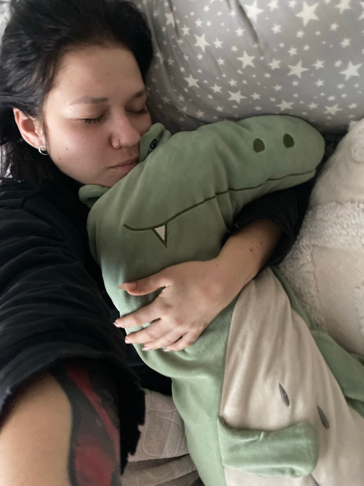 Person in dinosaur onesie rests in bed in Chaikovsky