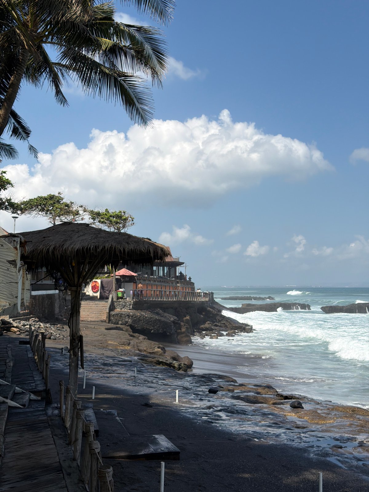 Rough surf and stormy skies hit North Kuta's black sand shore