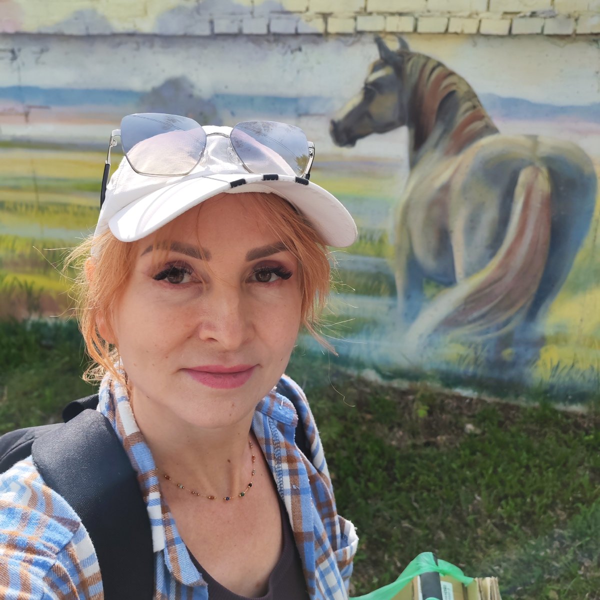 Woman takes selfies near rural mural in Chaikovsky