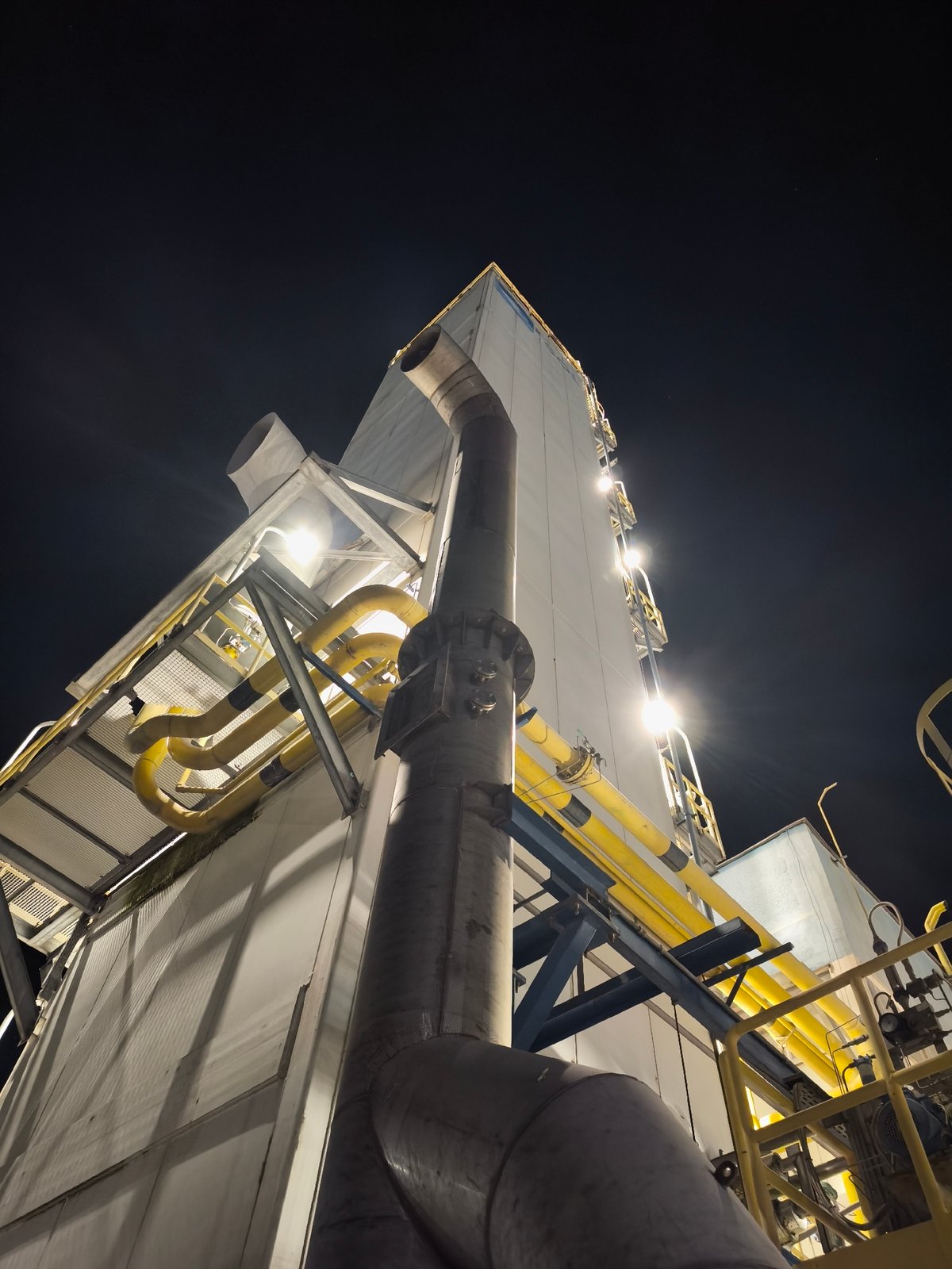 Nighttime industrial facility documentation captures tanks, pipes, emissions