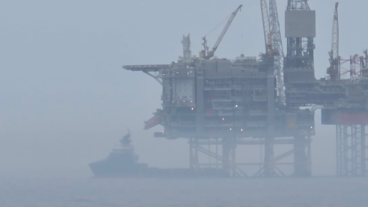 Red vessel operates near oil platform in foggy conditions