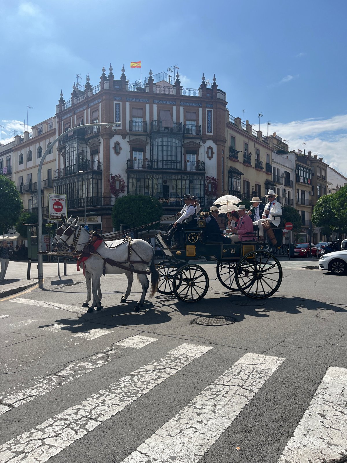 Horse carriage crosses pedestrian walkway in busy Seville square