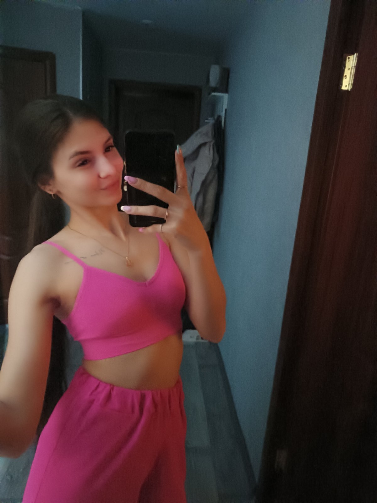 Woman takes selfies in pink outfit indoors