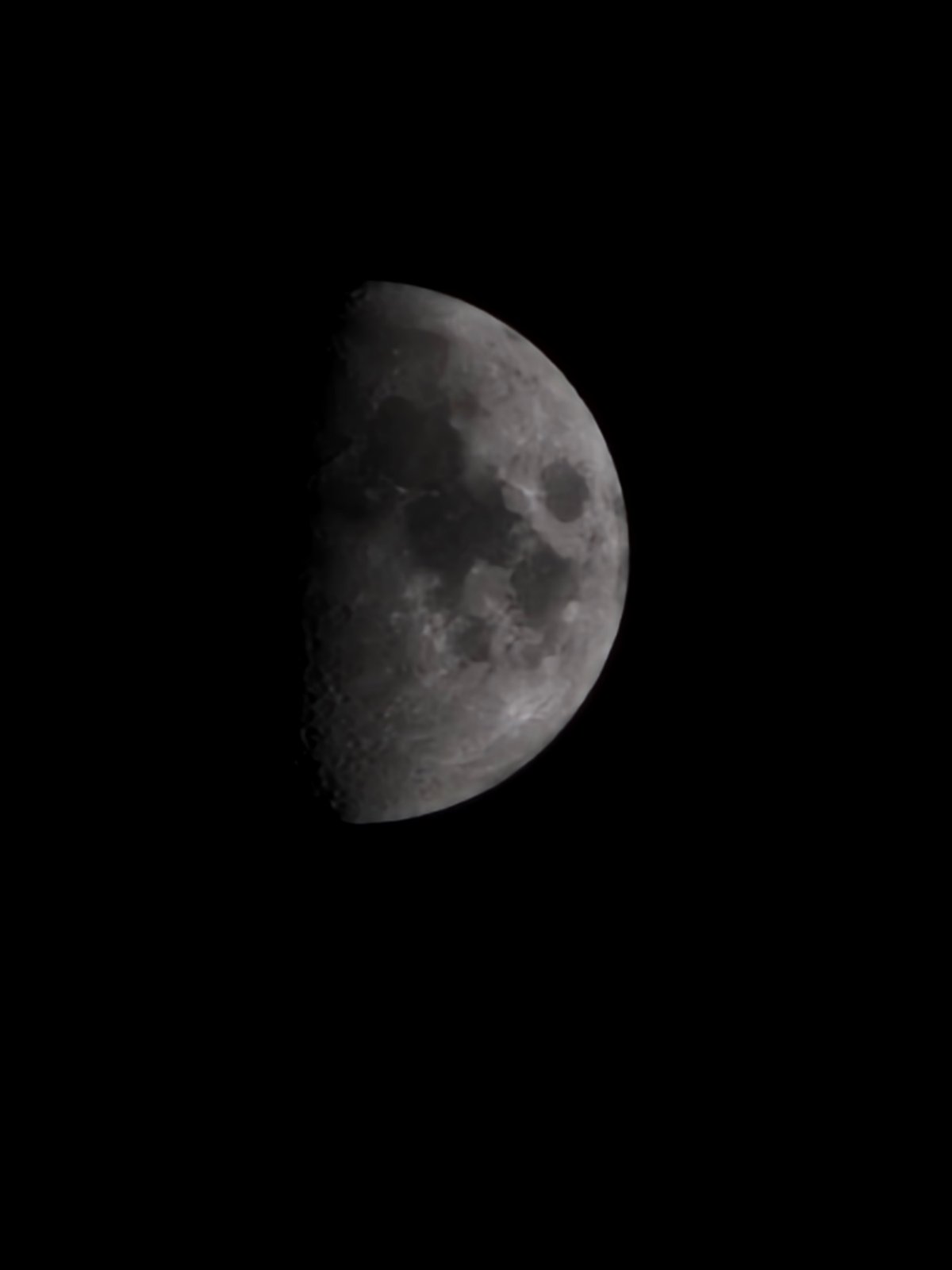 Half moon observed alongside artificial lighting in Karnobat, Bulgaria
