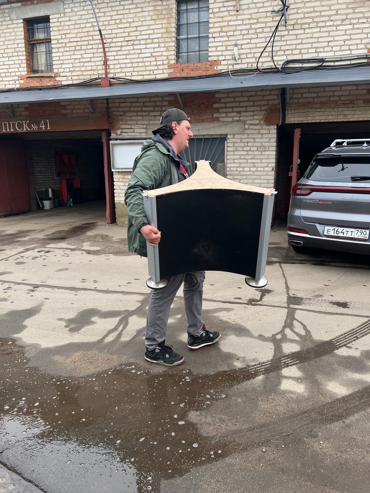 Men move wrapped object through Mytishchi garage complex