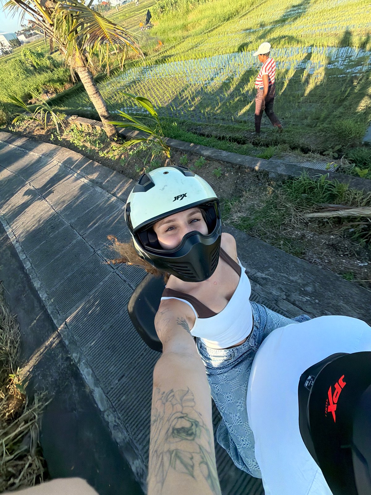 Woman takes motorcycle selfies near rice field in North Kuta