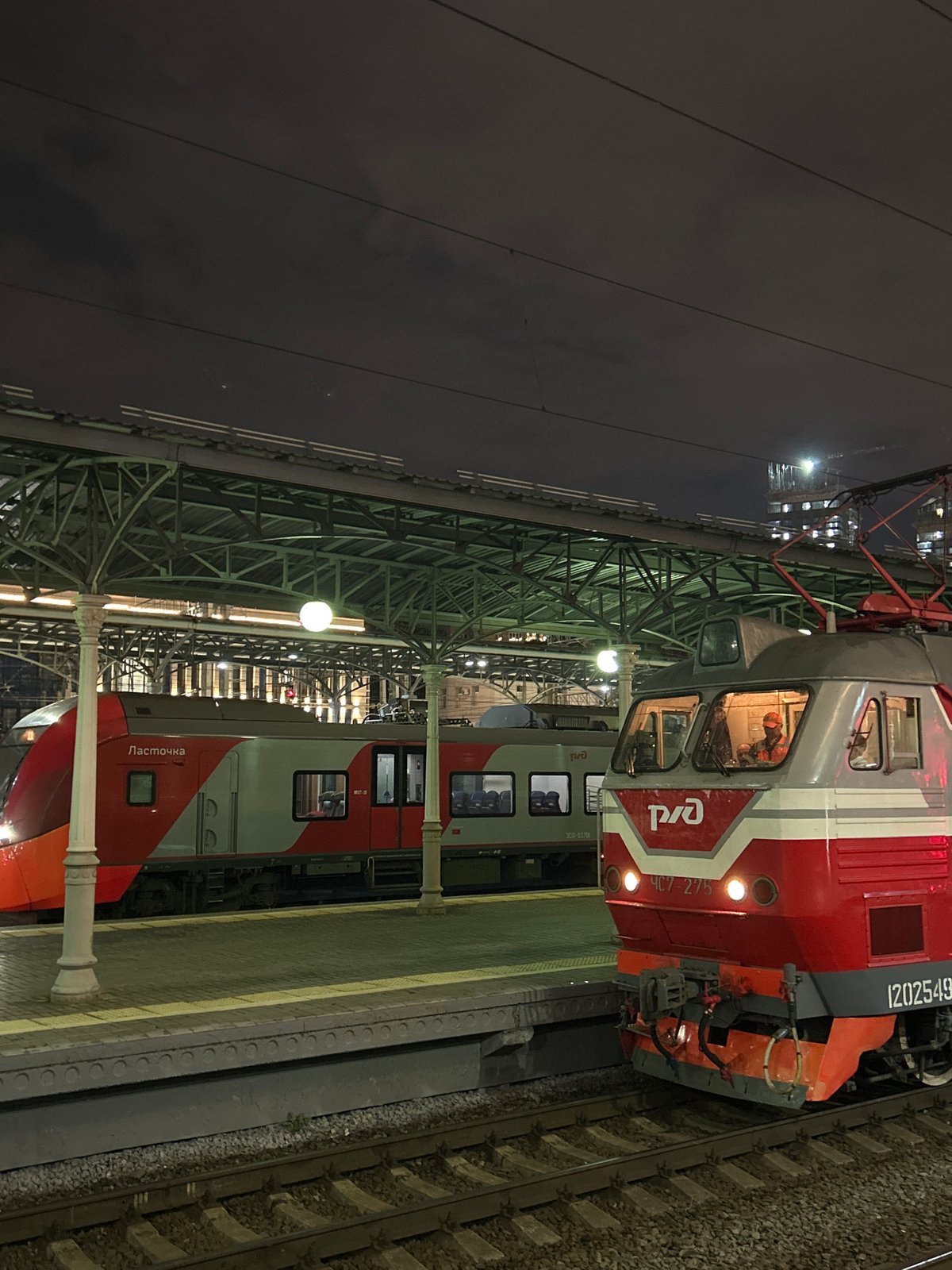Night scenes at a busy train station, multiple trains at platform