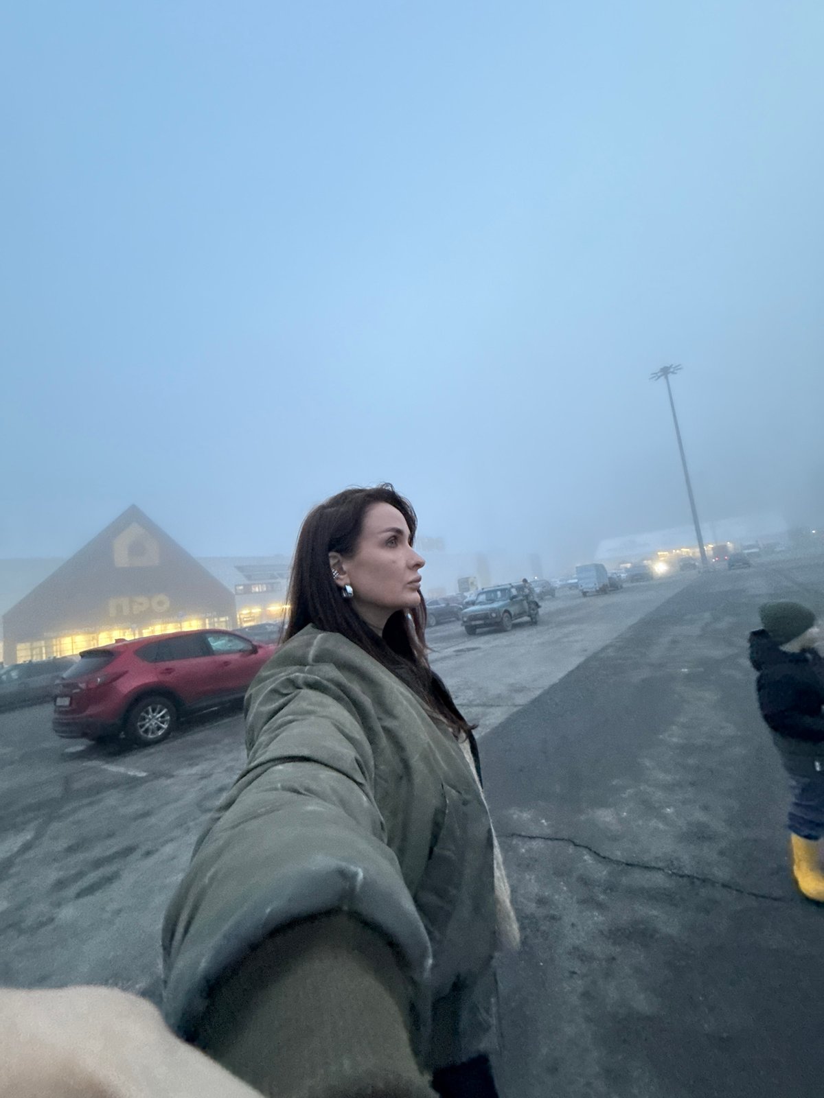 Woman stands in foggy parking lot outside Izhevsk store