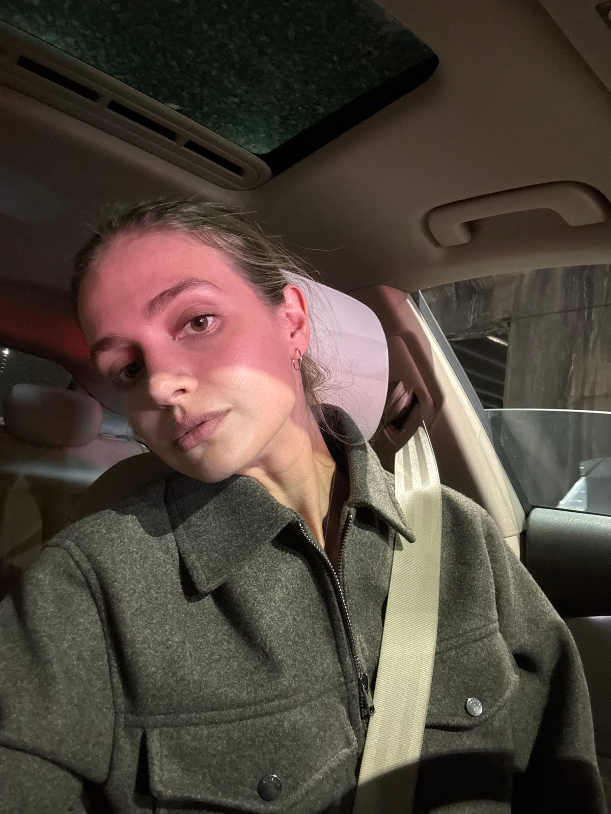 Woman in gray coat photographed during morning car ride