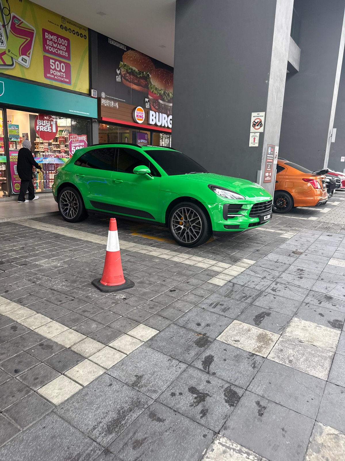 Green Porsche blocks pedestrian walkway near Kuala Lumpur shops