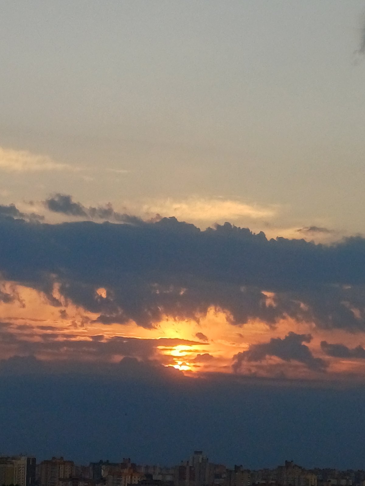 Urban sunset displays sectioned sky with contrasting cloud formations