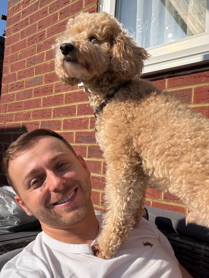 Man and curly-haired dog photographed outdoors in London