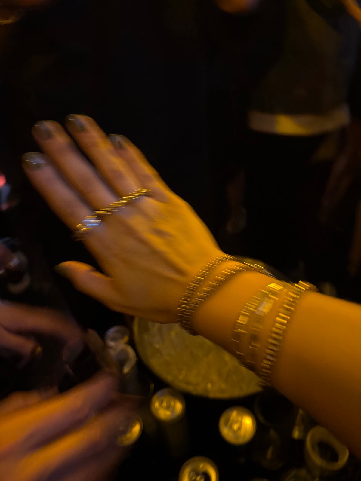 Person with gold jewelry reaches toward table in Mexico City
