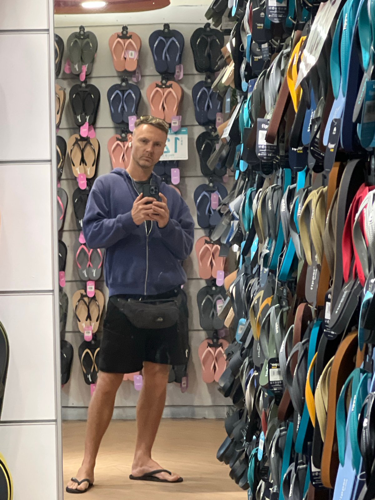 Man browses flip-flop display at Denpasar store