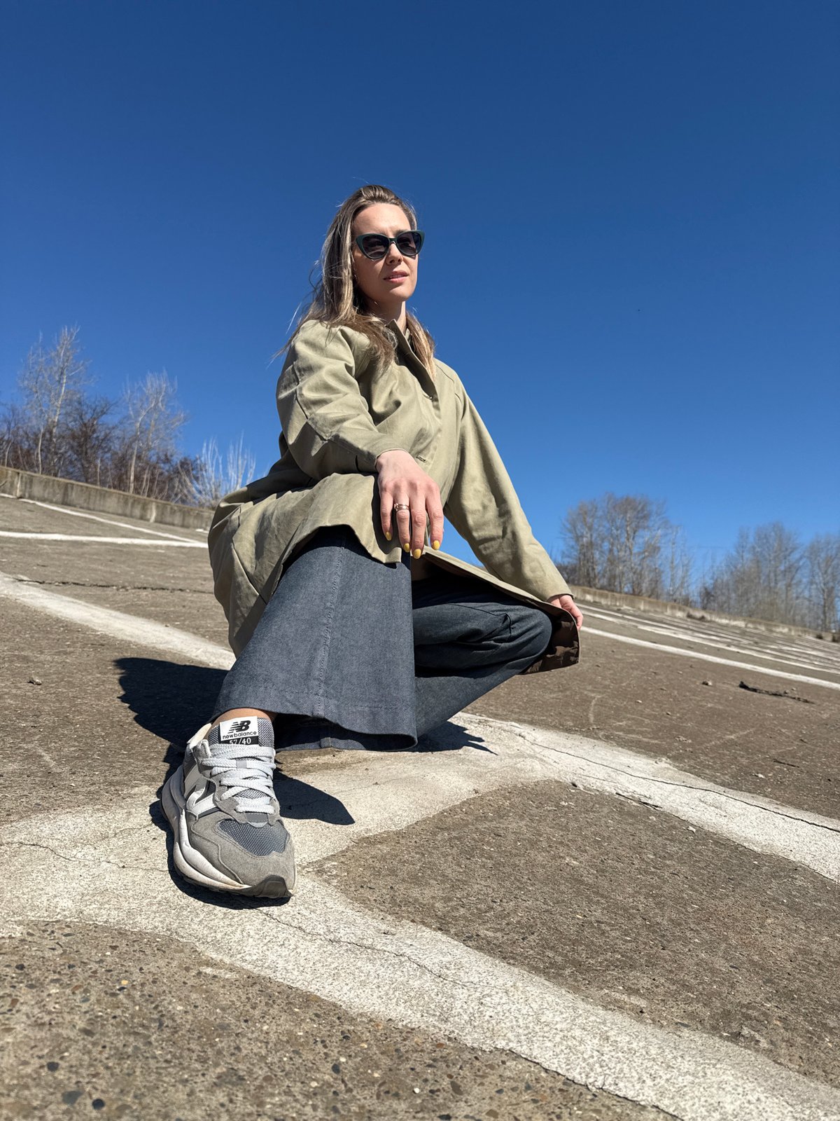 Woman sits in parking area under clear skies in Chaikovsky